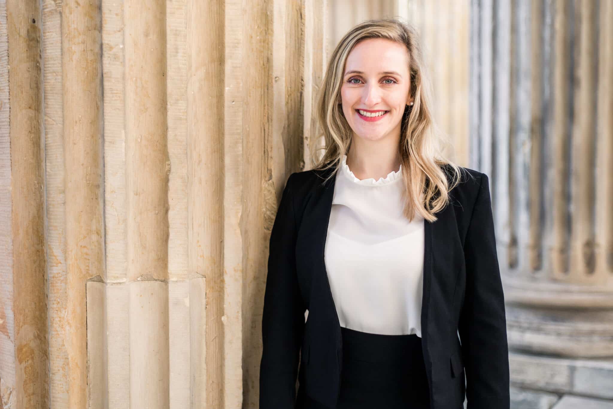 Blonde Spanisch-Dolmetscherin mit langen Haaren vor eine Ziegelsteinmauer